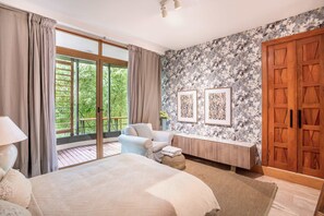 Ein Schlafzimmer mit Bett, Sitzecke, großem Fenster und Kleiderschrank.