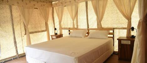 A large bed with a quilted mattress, a wooden headboard, and a nightstand with a lamp.