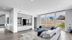 A modern living room with a large sofa, a glass coffee table, and a TV.