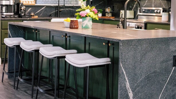 Uma cozinha moderna com uma ilha grande, banquetas e iluminação pendente.
