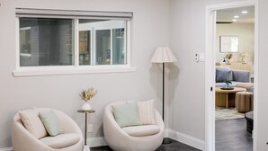 Quarto moderno com cama, duas cadeiras, abajur e ventilador de teto.