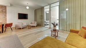 Ein modernes Wohnzimmer mit einer Couch, einem Sessel und einem an der Wand befestigten Fernseher.
