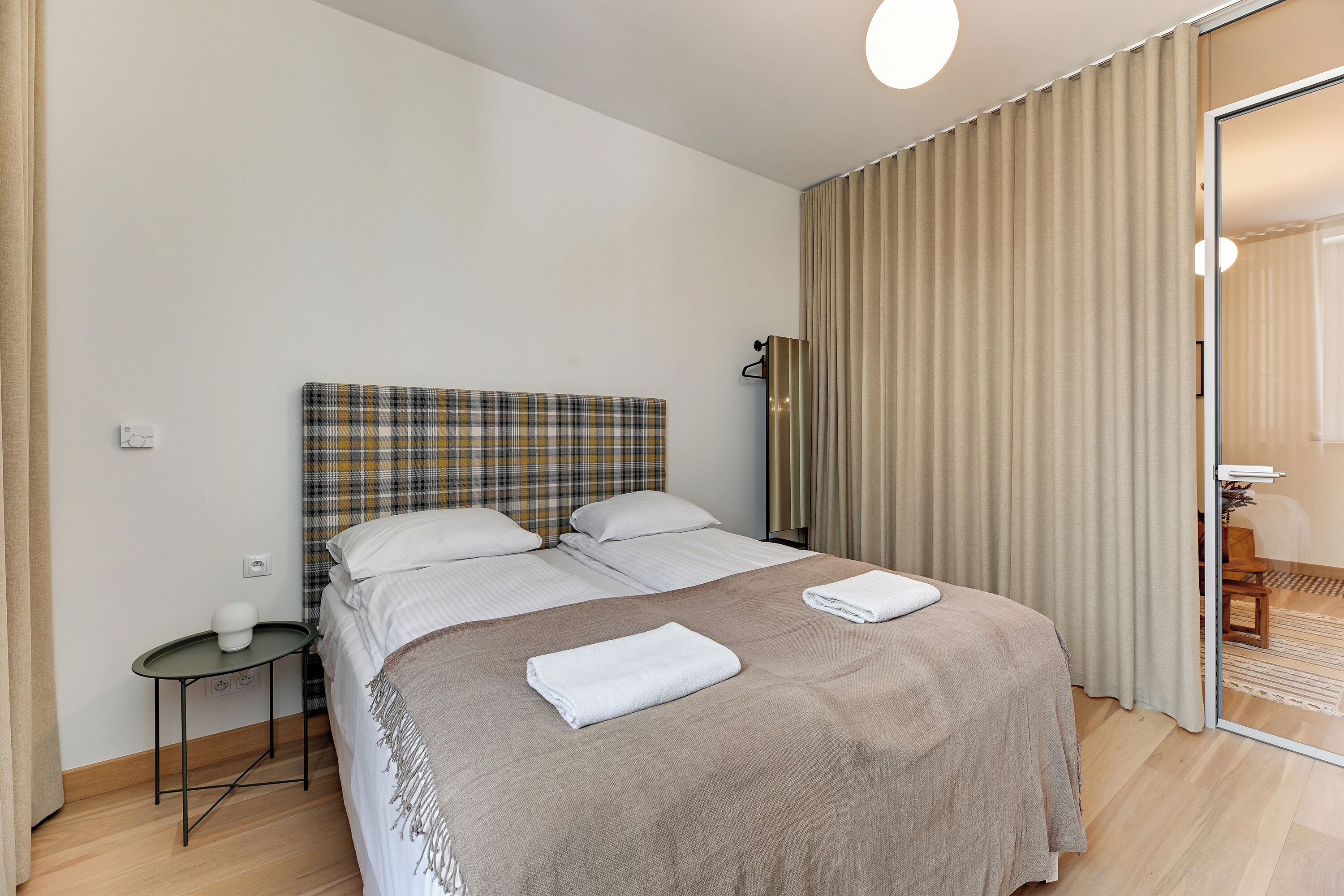 Una habitación de hotel con una cama, una mesita y un espejo.