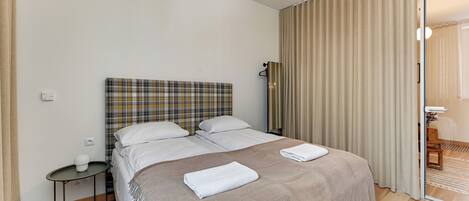 Una habitación de hotel con una cama, una mesita y un espejo.