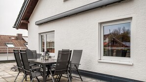 An outdoor patio with a table and chairs, a window, and a white building facade. - Holiday flat ‘Fewo Trudi’ with private terrace and Wi-Fi (Waltenhofen)