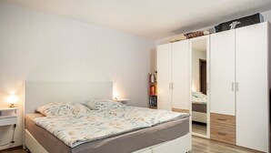A modern bedroom with a bed, bedside tables, a wardrobe, and a bookshelf. - Holiday flat ‘Fewo Trudi’ with private terrace and Wi-Fi (Waltenhofen)