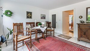 A dining area with a table, chairs, and a red patterned rug. - Apartment 'Deichblick' with Balcony and Wi-Fi (Wesselburenerkoog)