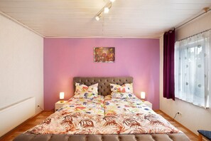 A bedroom with a bed, a nightstand, a wall art piece, and a window with curtains. - Failte Apartment with Scottish Charm and Wi-Fi (Selters (Taunus))