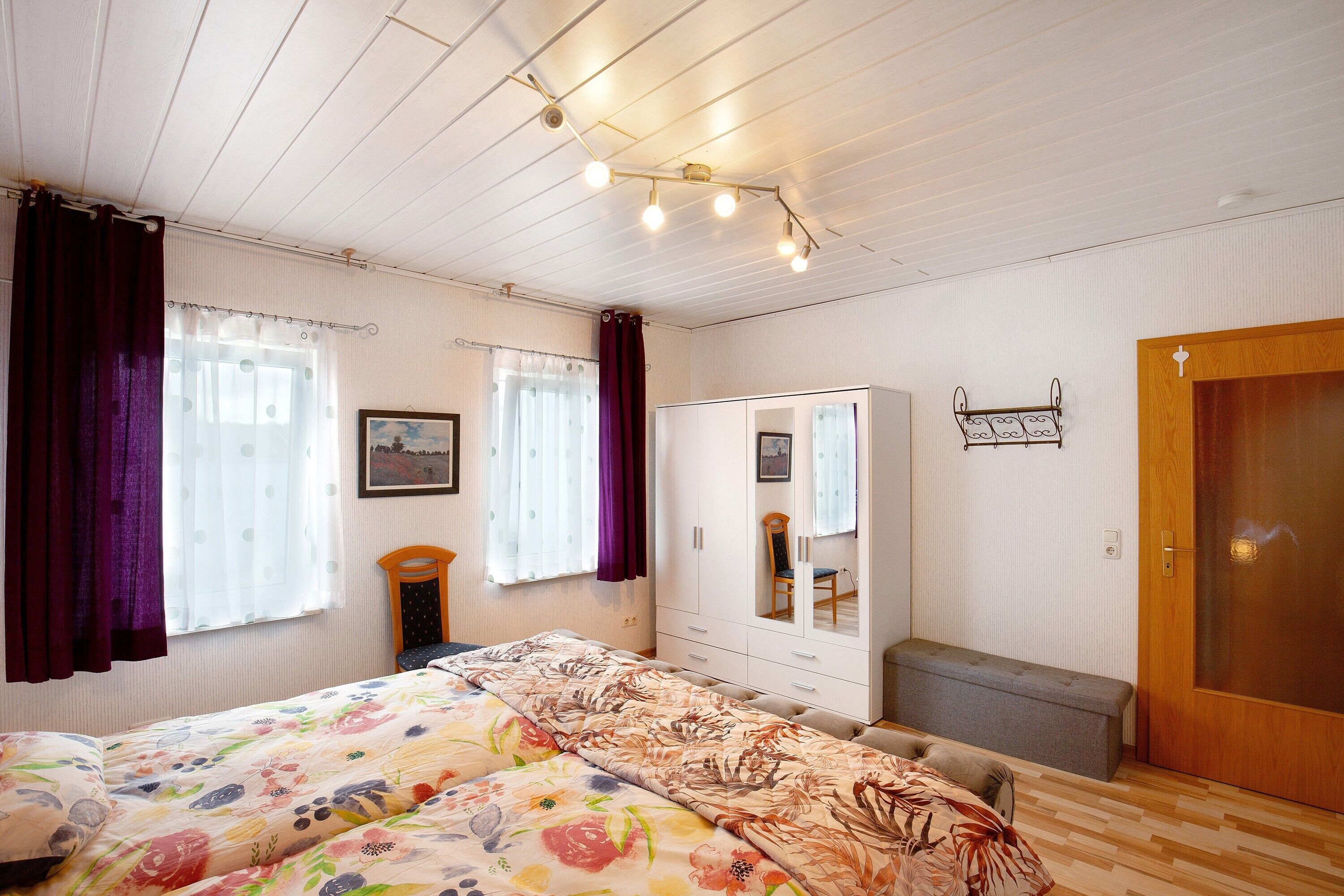 Ein Schlafzimmer mit einem Bett, einem Kleiderschrank, einer Bank und einer Tür.