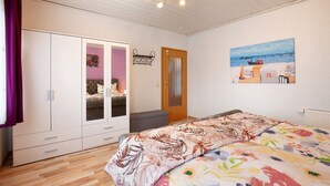 Un dormitorio con cama, armario y un cuadro en la pared.