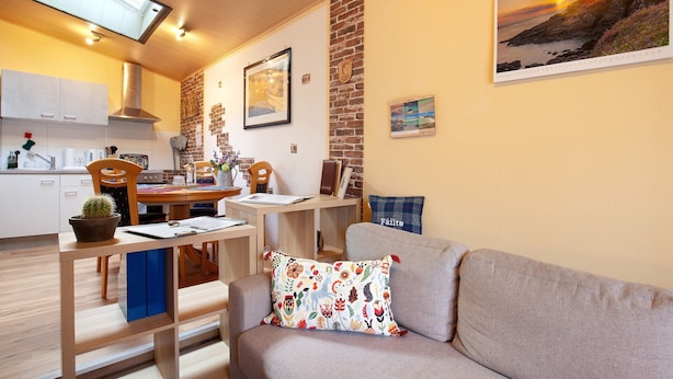 Una sala acogedora con un sofá, una mesa de comedor y una cocina al fondo.
