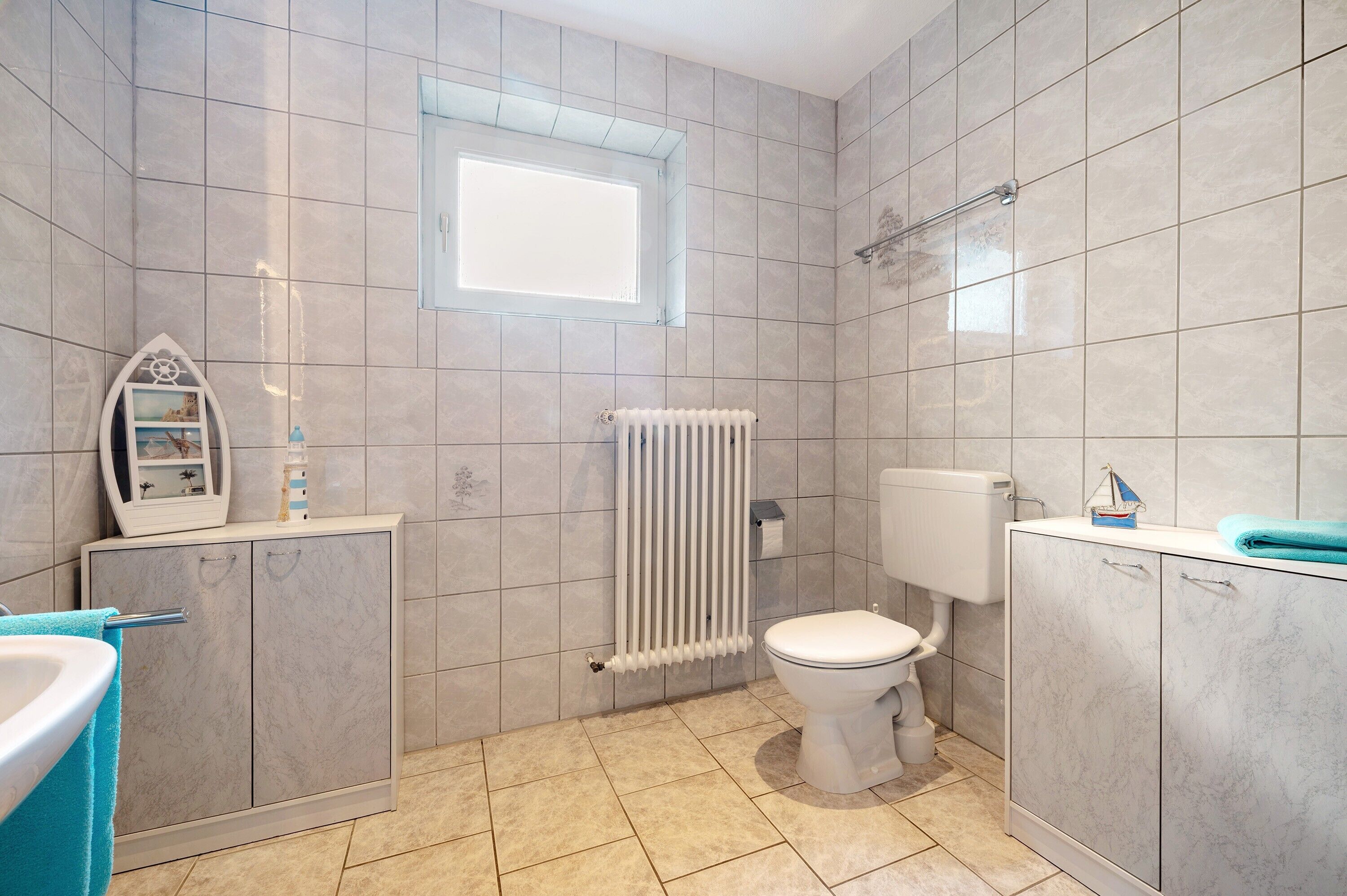 Un baño con inodoro, radiador, armario y ventana.