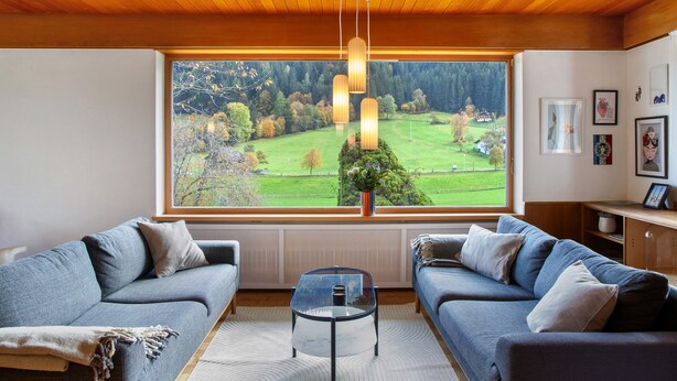A modern living room with two sofas, a coffee table, and a large window with a view of a green landscape. - Holiday Home 'Blueberry Haus Im Moos' with Mountain View, Shared Terrace and Wi-Fi (Oberau)