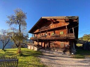 A wooden chalet with a balcony, a gravel driveway, and a bench in the foreground. - Chalet 'Berghof Moosen' with Mountain View, Private Terrace and Wi-Fi (Hart im Zillertal)