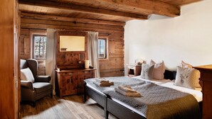 A wooden cabin bedroom with a bed, a chair, a dresser, and a window. - Chalet 'Berghof Moosen' with Mountain View, Private Terrace and Wi-Fi (Hart im Zillertal)