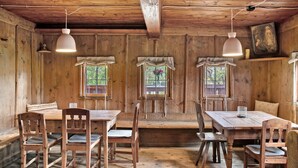 A rustic wooden cabin with a dining area featuring wooden tables and chairs, a bench, and a hanging light fixture. - Chalet 'Berghof Moosen' with Mountain View, Private Terrace and Wi-Fi (Hart im Zillertal)