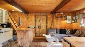Interior de una cabaña de madera con cocina, comedor y sofá.
