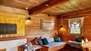 L'interno di una casetta in legno con una panca, un divano, un tavolo e una finestra con tende.
