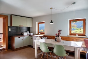 A kitchen with a white table, green chairs, and a window with a view of trees.