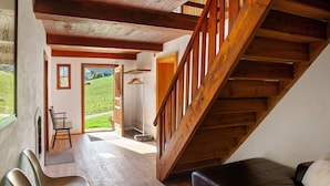 Un'ampia stanza con una scala in legno, un divano in pelle e vista su un paesaggio verde.