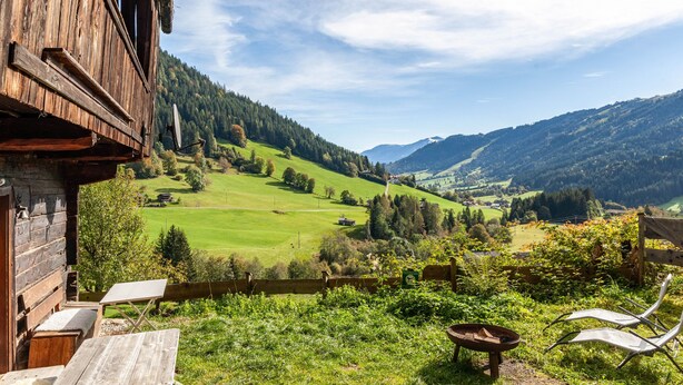 A wooden cabin with a balcony overlooking a green valley and mountains. - Apartment 'Ground Floor' with Mountain View, Private Terrace and Garden (Oberau)