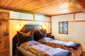 Una habitación con paneles de madera, dos camas, una ventana y una puerta.