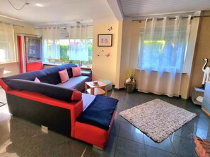 Un salon moderne avec un canapé, une petite table, un tapis, une plante en pot et un objet décoratif posé sur une commode.