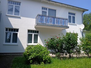 Une maison à deux étages dotée d’un balcon, de fenêtres et d’une antenne parabolique.