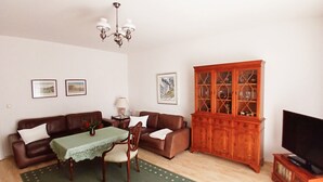 Ein Wohnzimmer mit einem braunen Sofa, einem grünen Tisch, einem Holzschrank und einem Fernsehschrank.