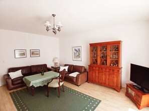Una sala de estar con un sofá marrón, una mesa verde, un aparador de madera y un mueble para televisión.