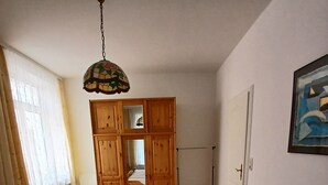 Ein Schlafzimmer mit zwei Betten, einem Holzschrank, einer Hängeleuchte und einem Bild an der Wand.