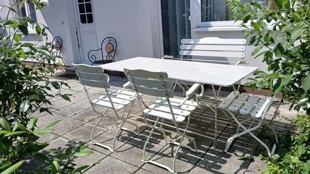 Un patio con una mesa, sillas, una puerta y una ventana.