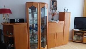Una sala de estar con un aparador de madera, un televisor y una estantería.
