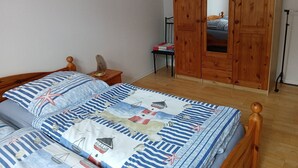Un dormitorio con una cama de madera, una mesita de noche, un armario de madera y un espejo.