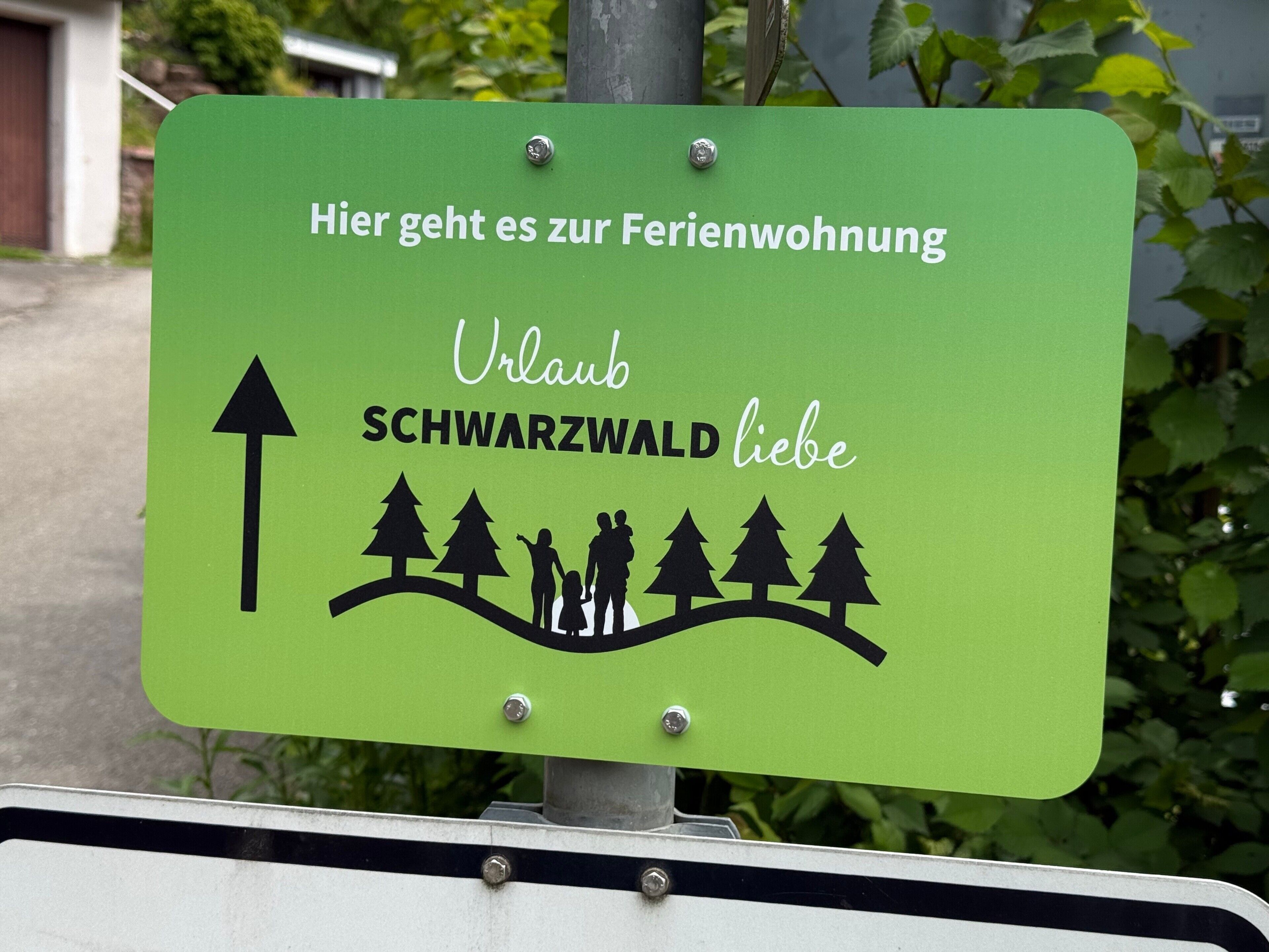 En vägvisningsskylt med text på tyska som visar vägen till ett fritidshus i Schwarzwald.