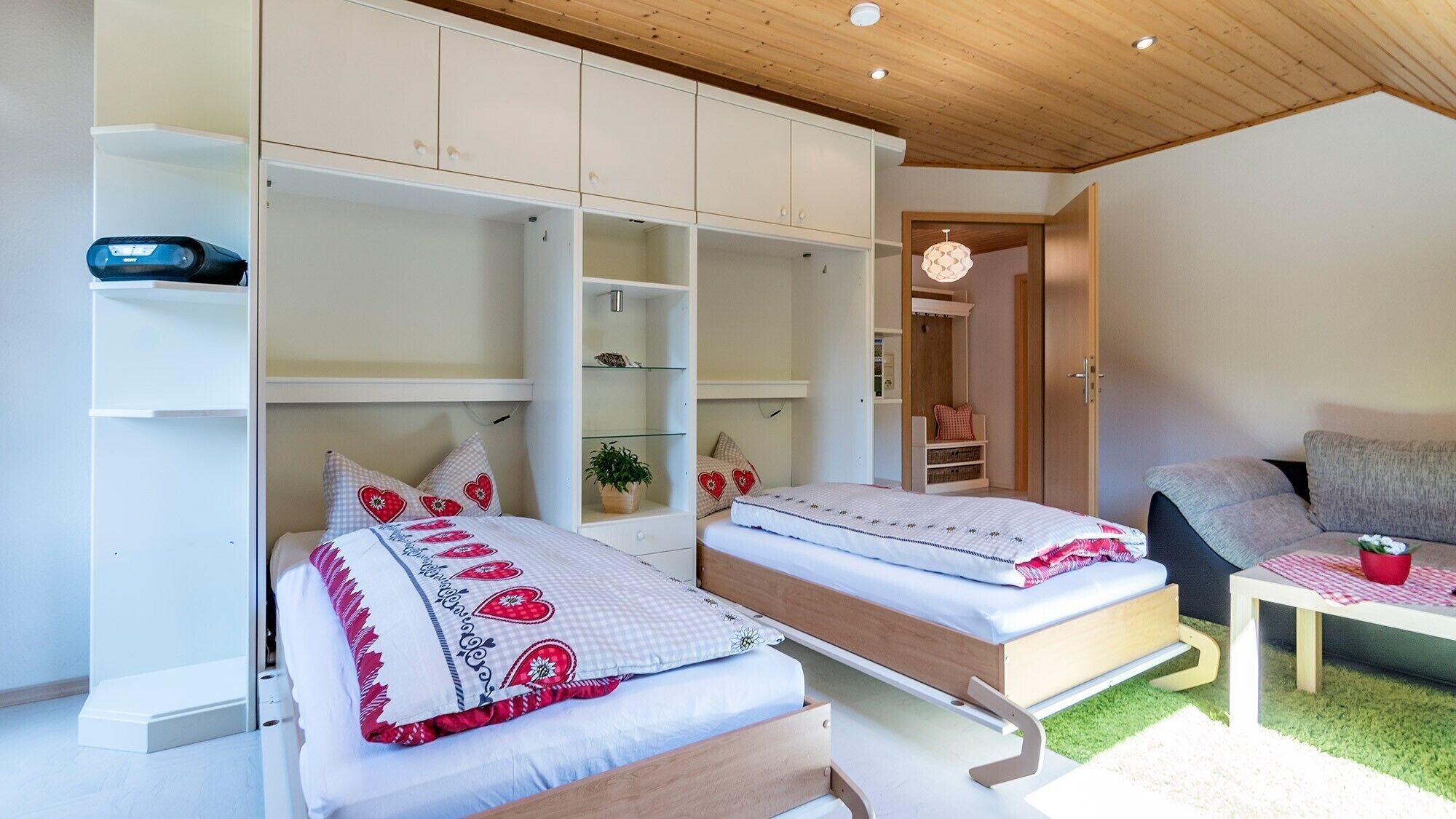 Een slaapkamer met twee bedden, een slaapbank, een kleine tafel en inbouwkasten.