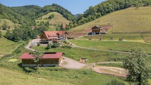 Un entorno rural con una casa grande, construcciones más pequeñas y un cercado con vacas.