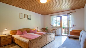 A bedroom with a wooden bed, a nightstand, a dresser, a window with a view, and a balcony.