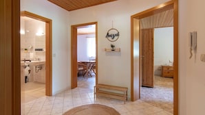 A hallway with a wooden bench, a wall-mounted sign, and a tiled floor.
