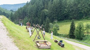 A playground with swings, a slide, and a sandbox in a grassy area with trees. - Apartment ‘Tannenhöhe’ with mountain view, balcony and Wi-Fi (Oppenau)
