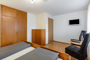 Ein Schlafzimmer mit Bett, Kleiderschrank, Schreibtisch, Stuhl und Fernseher.