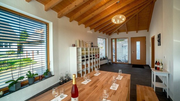 A room with a wooden ceiling, a wine rack, a table set for dining, and a view through large windows. - Room 'Doppelzimmer 3 - Chardonnay' with Shared Terrace, Shared Garden and Wi-Fi (Bad Bellingen)