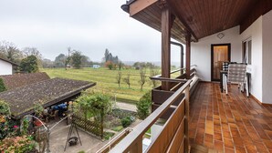 A balcony with a view of a garden and a building in the background. - Room 'Doppelzimmer 3 - Chardonnay' with Shared Terrace, Shared Garden and Wi-Fi (Bad Bellingen)
