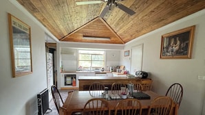 A dining area with a wooden table and chairs, a ceiling fan, and a kitchen in the background. - Enjoy Alpine Lifestyle at Mesley Manor, in heart of Omeo, close to Bike Trails (Omeo)