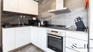 Una cocina moderna con armarios blancos, un horno Bosch y una encimera negra.
