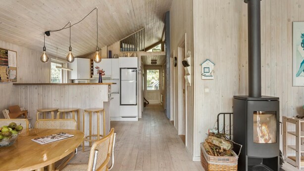 A spacious kitchen with wooden walls, a central island, and a wood-burning stove.