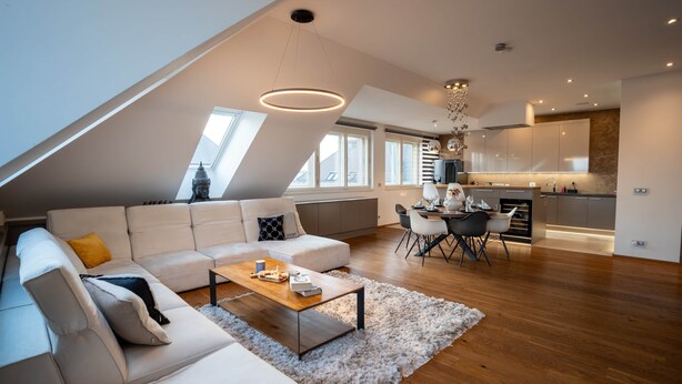 A modern loft apartment with a dining area, kitchen, and a large window overlooking a cityscape. - Prague Spa Penthouse (Hlavní město Praha)