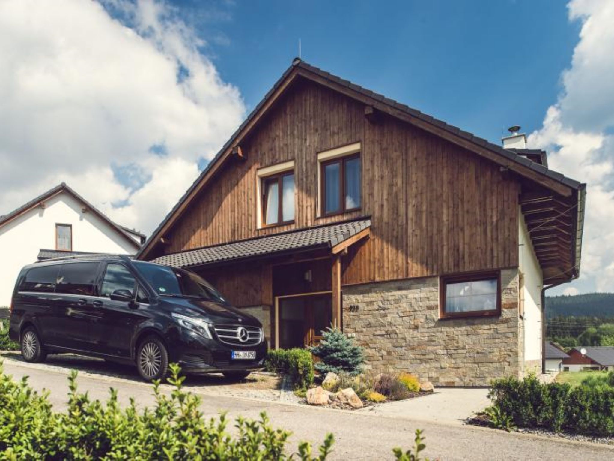 A modern two-story house with a stone facade and a wooden roof.