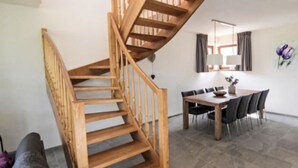 Een modern interieur met een houten trap die leidt naar een eethoek.