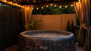 A hot tub with a marble design, surrounded by a wooden deck and a covered area with string lights. - Vintage RV & SPA Experience for 3 (Dover)